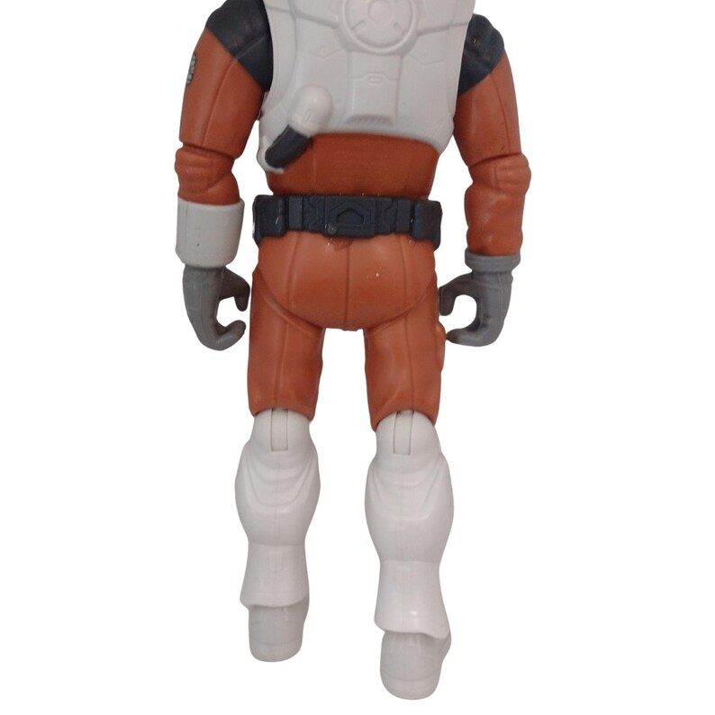 May include: A toy action figure of a space explorer, viewed from the back. The figure is wearing an orange jumpsuit with white accents on the chest, boots, and cuffs. The figure has gray gloves and a black belt. The figure is standing.