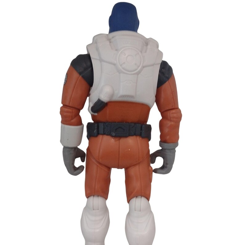 May include: A toy action figure of a space explorer, viewed from the back. The figure is wearing an orange jumpsuit, a white vest with a circular design, and a blue helmet. The gloves and boots are gray and white.