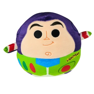 May include: A plush toy shaped like Buzz Lightyear from Toy Story. The toy has a purple head, a tan face with black eyes, and a green and blue body. The word "LIGHTYEAR" is printed on the front.