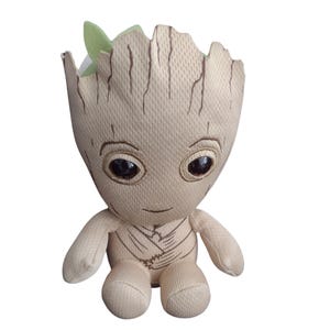 Pode incluir: Um brinquedo de pelúcia marrom e bege do personagem Groot da franquia Guardiões da Galáxia. O brinquedo tem uma folha verde na cabeça e grandes olhos pretos.
