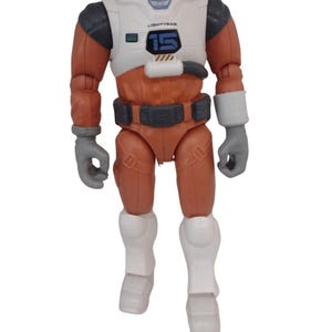 May include: A Buzz Lightyear action figure in a space suit. The figure is primarily orange, white, and gray, with the word "LIGHTYEAR" and the number "15" visible on the chest. The figure has a detailed belt and boots.