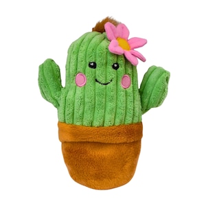 May include: A plush cactus toy with a ribbed green body, two side arms, and a brown pot base. The cactus features a smiling face with black embroidered eyes, a curved mouth, and pink circular cheeks. A bright pink flower with a yellow centre sits on top.