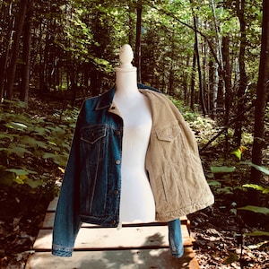 Op de afbeelding: Een spijkerjack met een corduroy voering. Het jack wordt getoond op een mannequin in een bosrijke omgeving.