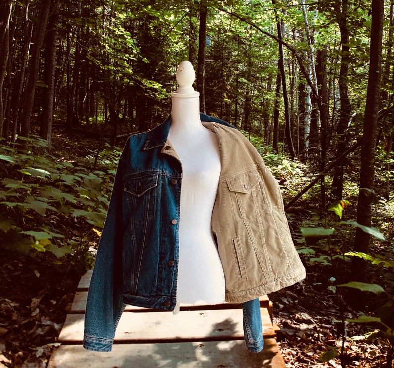Op de afbeelding: Een spijkerjack met een corduroy voering. Het jack wordt getoond op een mannequin in een bosrijke omgeving.