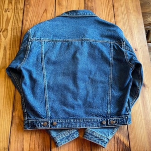 Op de afbeelding: Een blauwe denim jas met een klassiek ontwerp. De jas heeft een knoopsluiting, lange mouwen en twee zakken op de borst.