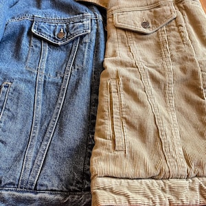 Op de afbeelding: Een spijkerjack met een corduroy jack dat aan de rechterkant is genaaid. Het spijkerjack is blauw en het corduroy jack is bruin.