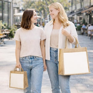Puede incluir: Dos bolsas de mano rectangulares de yute con paneles blancos s&oacute;lidos en la parte frontal. La bolsa m&aacute;s peque&ntilde;a tiene asas cortas, mientras que la m&aacute;s grande tiene asas m&aacute;s largas. Ambas bolsas est&aacute;n hechas de tela de yute tejida en color canela.