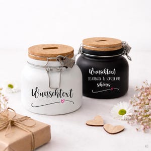 Könnte beinhalten: Zwei Keramikgläser mit Korkdeckeln und Metallbügelverschluss, eines in Weiß und eines in Schwarz. Das weiße Glas trägt den Text "Wunschtext" mit einem kleinen rosa Herz. Das schwarze Glas zeigt "Wunschtext SEI KREATIV & SCHREIB WAS schönes".