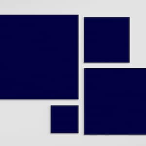 May include: Four navy blue square frames of different sizes arranged on a white wall.