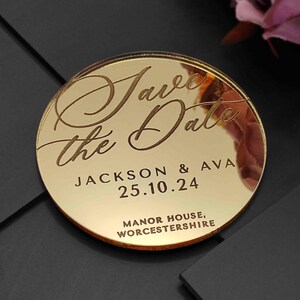 May include: A circular, gold-coloured wedding announcement with the words "Save the Date" in elegant script. The names "Jackson & Ava" and the date "25.10.24" are engraved. The location "Manor House, Worcestershire" is at the bottom.