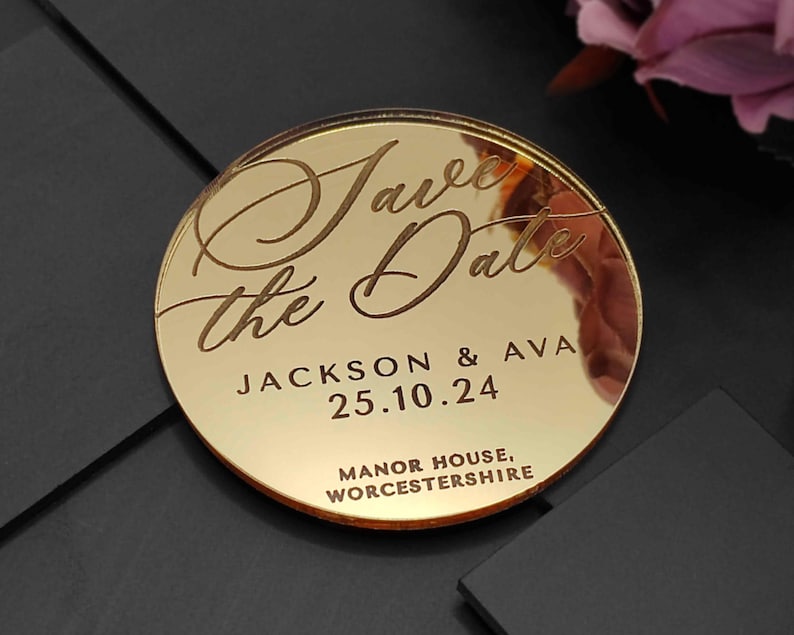 May include: A circular, gold-coloured wedding announcement with the words "Save the Date" in elegant script. The names "Jackson & Ava" and the date "25.10.24" are engraved. The location "Manor House, Worcestershire" is at the bottom.