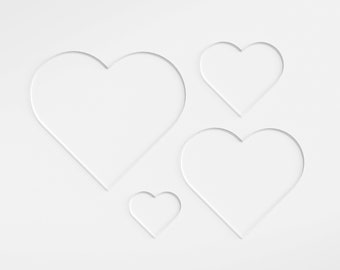 May include: Four white paper hearts of different sizes are cut out of a white background. The hearts are arranged in a staggered pattern.
