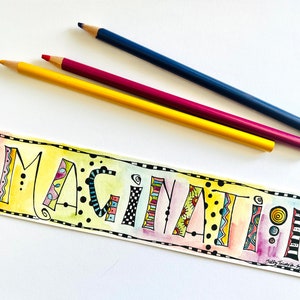 以下が含まれることがあります： 「IMAGINATION」という単語が、幻想的なフォントで書かれたカラフルな手描き看板。文字は、ストライプ、水玉模様、渦巻きなど、さまざまなパターンと色で飾られています。看板は、白黒の市松模様の枠で囲まれています。