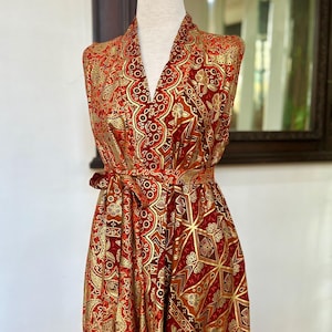 May include: A sleeveless red and gold patterned robe with a V-neck and a tie belt.