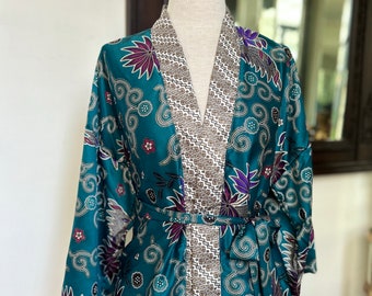 May include: Teal blue silk robe with a floral pattern and a brown and white patterned lining. The robe has a tie belt and long sleeves.