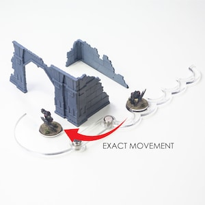 May include: A tabletop gaming scene with miniature figures and terrain. The scene includes gray, ruined building structures, miniature figures on circular bases, and a clear acrylic movement guide. The text "EXACT MOVEMENT" is visible.