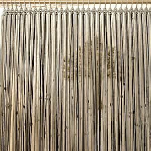 Puede incluir: Un primer plano de una cortina de macramé hecha con cuerda negra y blanca. La cortina está colgada de una barra de metal y está compuesta por muchos hilos individuales de cuerda.