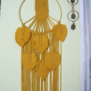 May include: A mustard yellow macrame wall hanging with a circular hoop and multiple feather-shaped tassels.