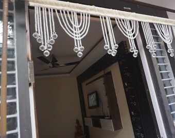 May include: White beaded door curtain with crystal beads hanging from the bottom. The curtain is hung on a white fabric rod.