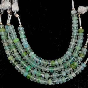 Könnte beinhalten: Eine Strähne aus hellgrünen und blauen facettierten Edelsteinperlen. Die Perlen sind auf einem Silberdraht aufgefädelt und haben eine polierte Oberfläche.