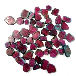 May include: A collection of loose ruby gemstones, each with a unique shape and size. The rubies are a deep red colour with a hint of blue.
