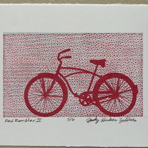 May include: A red bicycle illustration titled "Red Rambler II" on a white background. The bicycle is a classic cruiser style, with a curved frame and large wheels. The background is a textured pattern of red dots.