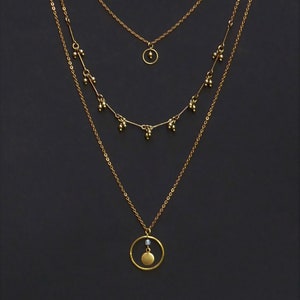 3-row necklace composed of 2 pendants and a chain with charms and a small white or black boho crystal bead.