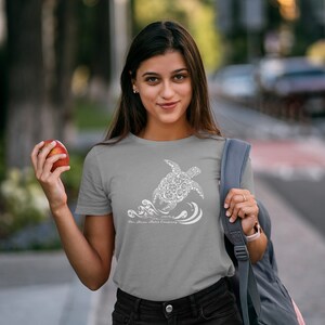 Puede incluir: Una camiseta gris con un gr&aacute;fico blanco de una tortuga hecha de c&iacute;rculos m&aacute;s peque&ntilde;os y olas. El texto "The Aloha Shirt Company" est&aacute; impreso debajo de la tortuga.