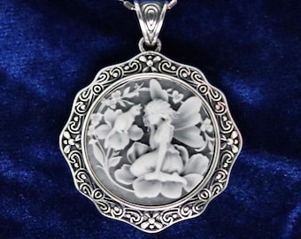 May include: A silver-toned pendant necklace featuring a circular cameo with a white relief of a winged fairy sitting on a flower, surrounded by an ornate scalloped metal frame. The text Fairy C is printed in the upper right corner of the image.