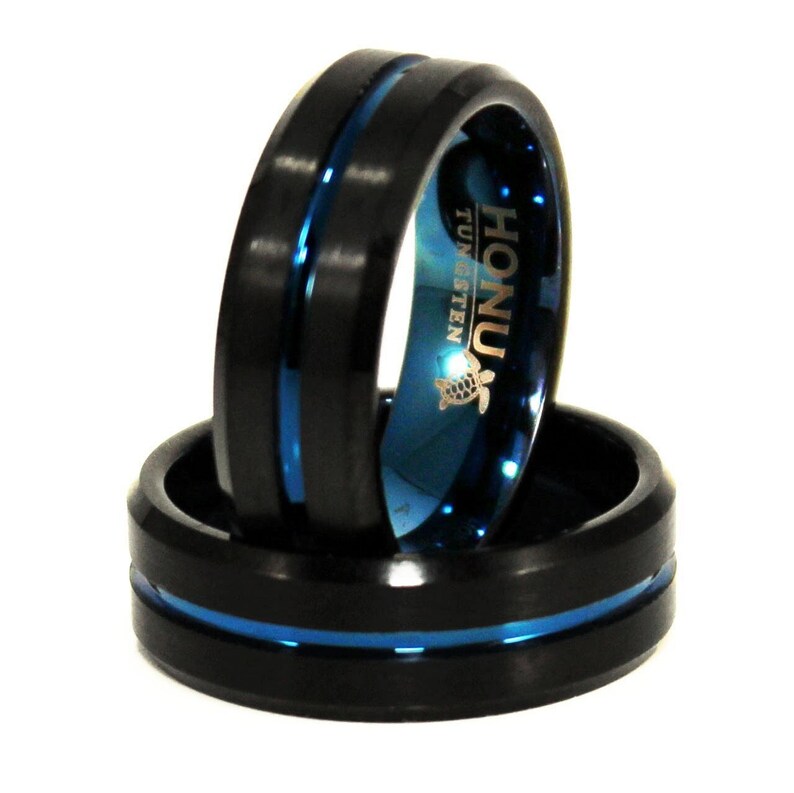 K&ouml;nnte beinhalten: Zwei schwarze Ringe aus Wolframcarbid mit einer blauen Einlage. Der obere Ring hat das Wort "HONU" und "TUNGSTEN" auf der Seite eingraviert.