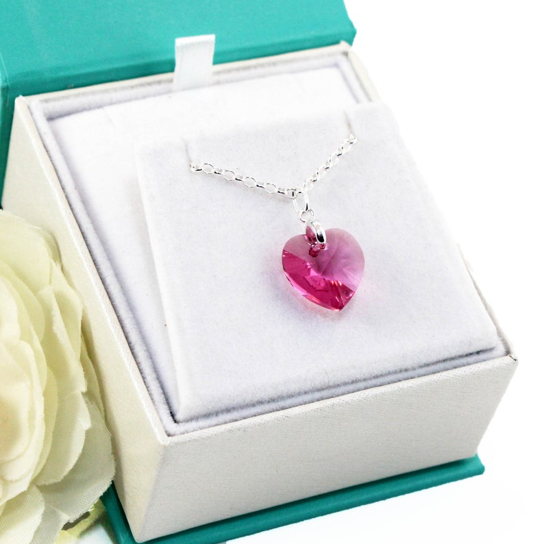 Op de afbeelding: Een zilveren ketting met een roze kristallen hart hanger in een witte geschenkdoos.