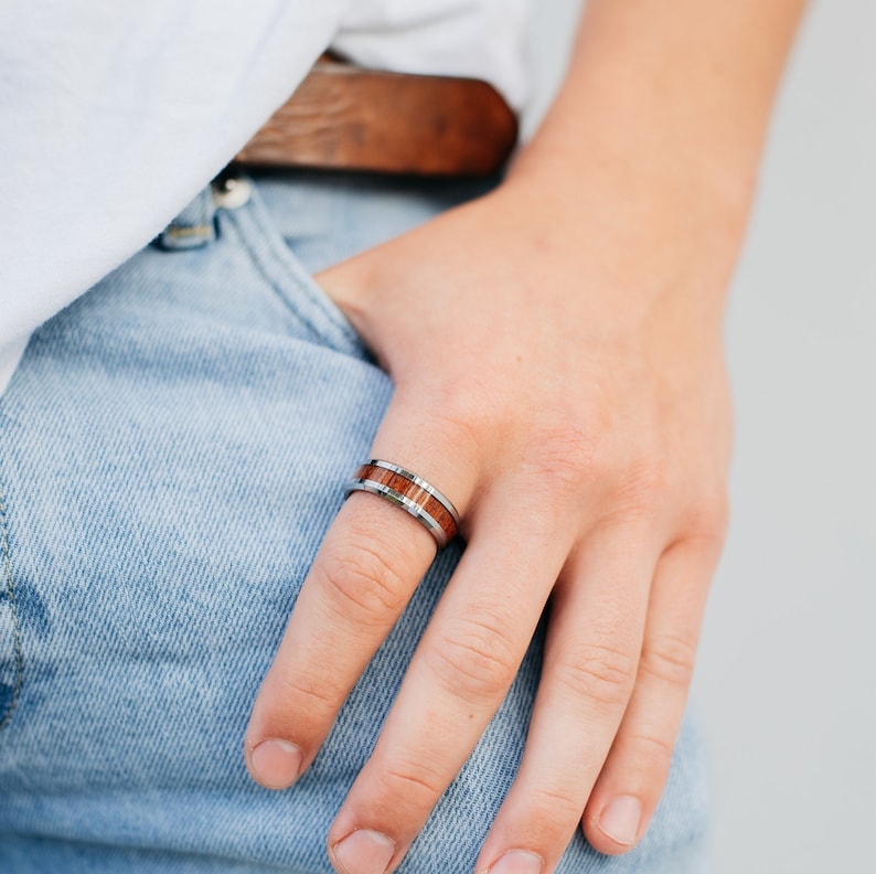 May include: A silver and brown wood ring with a thin silver band and a brown wood inlay.
