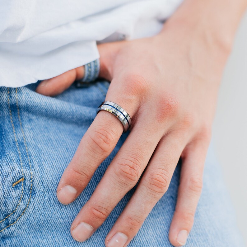 K&ouml;nnte beinhalten: Ein silberner Ring mit zwei blauen Linien um das Band.