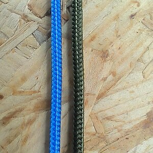 K&ouml;nnte beinhalten: Zwei St&uuml;cke geflochtenes Seil, eines blau und eines gr&uuml;n, werden vor einem Holzgrund gezeigt.