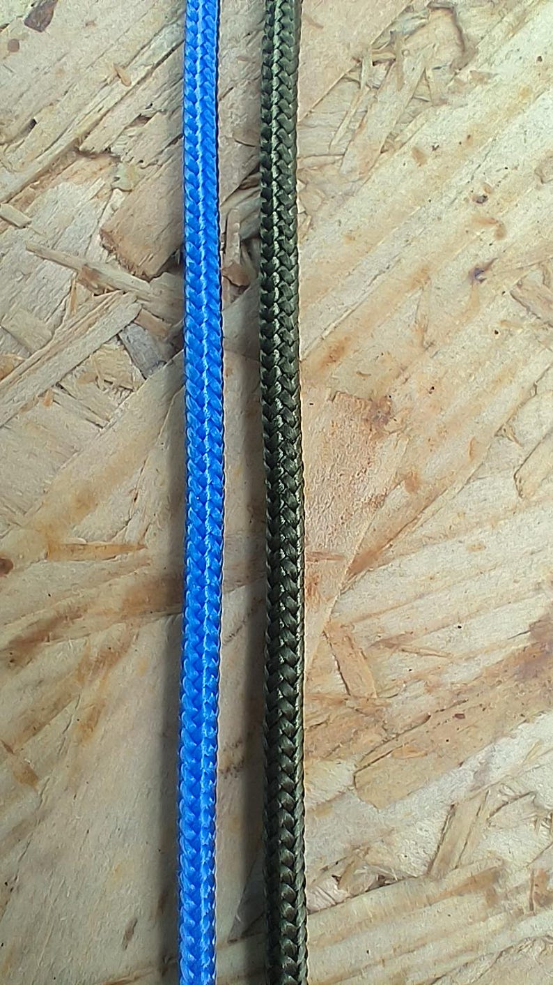 K&ouml;nnte beinhalten: Zwei St&uuml;cke geflochtenes Seil, eines blau und eines gr&uuml;n, werden vor einem Holzgrund gezeigt.