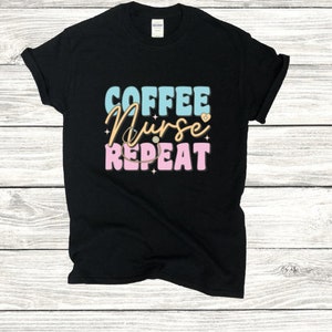 May include: Black t-shirt with the text "COFFEE NURSE REPEAT" in blue, pink, and white lettering. A stethoscope and a heart are included in the design.