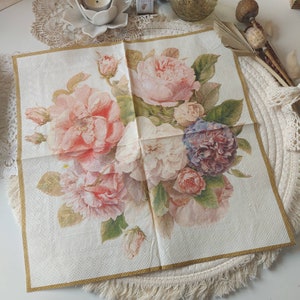 Pode incluir: Um guardanapo de papel branco com uma borda dourada apresenta um desenho floral com rosas cor-de-rosa, brancas e roxas. As rosas estão dispostas em um buquê com folhas verdes.