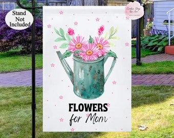 May include: A white garden flag with a watercolor illustration of pink flowers in a green watering can. The text "FLOWERS for Mom" is printed in black below the watering can.