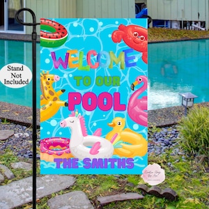 May include: A blue and pink welcome to our pool yard sign with a unicorn, flamingo, and other pool float designs. The sign says "Welcome to our Pool The Smiths".