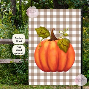 May include: A double-sided garden flag featuring a large orange pumpkin with green leaves. The pumpkin has the words "Fuck" and "Trump" on the leaves. The background is a brown and white checkered pattern.