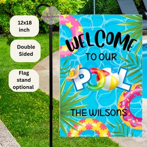 May include: Welcome to our pool yard flag with a blue background, colorful pool floats, palm leaves, and the text "Welcome to our Pool The Wilsons".