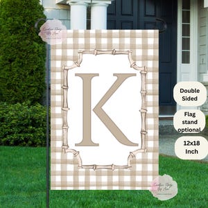 May include: A double-sided garden flag with a tan and white gingham pattern. The flag features a large letter "K" in a light brown color, framed by a bamboo-style border. The flag measures 12x18 inches.