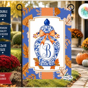 May include: A rectangular garden flag featuring a blue and white ginger jar with a large orange bow and the letter B in the center. The background displays orange and brown autumn leaves on a blue field. Text includes DOUBLE SIDED, PREMIUM QUALITY POLYESTER, 12x18 SIZE, and FLAG STAND NOT INCLUDED.