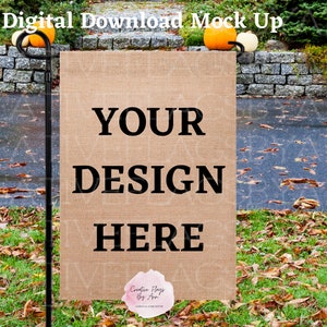 Może przedstawiać: Brązowa flaga ogrodowa z juty z tekstem "YOUR DESIGN HERE"  wyświetlonym na niej. Flaga jest przymocowana do czarnego metalowego drążka i jest wyświetlana w ogrodzie z jesiennymi liśćmi.