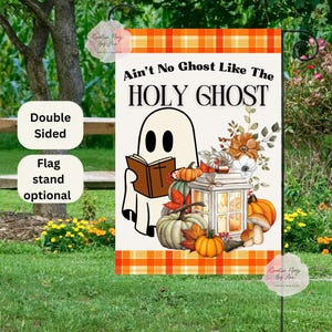 May include: A double-sided garden flag with the text "Ain't No Ghost Like The HOLY GHOST." The flag features a cartoon ghost reading a book, pumpkins, and floral accents. The flag has an orange and white plaid border.