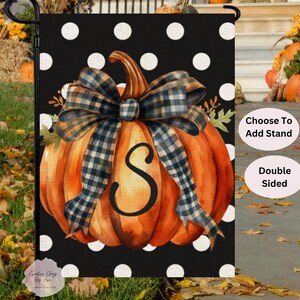 May include: A double-sided garden flag featuring a watercolor-style orange pumpkin with a plaid bow and the letter "S". The background is black with white polka dots. Text on the flag reads "Choose To Add Stand" and "Double Sided".