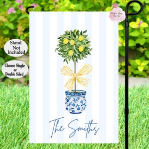 May include: A blue and white ceramic pot with a yellow bow holds a lemon tree with green leaves and yellow lemons. The text "The Smiths" is printed below the pot on a white and blue striped background.