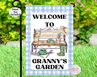 May include: A blue and white gingham garden flag with the text "Welcome to Granny's Garden" and a watercolor illustration of a bench with gardening tools and a hat.