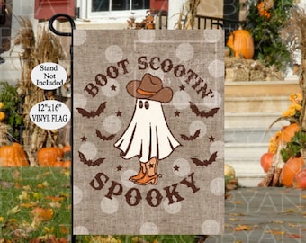 May include: A 12"x16" vinyl flag with a Halloween theme. The flag features a ghost wearing a cowboy hat and boots, with the words "Boot Scootin' Spooky" in a western font. Brown bats and stars decorate the background.