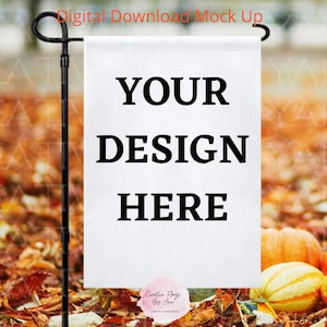 Puede incluir: Una bandera de jardín blanca con texto negro que dice "YOUR DESIGN HERE". La bandera está unida a una estaca de metal negro y se muestra en un montón de hojas de otoño. El texto "Creative Flags By Apa" está impreso en la esquina inferior derecha de la bandera.